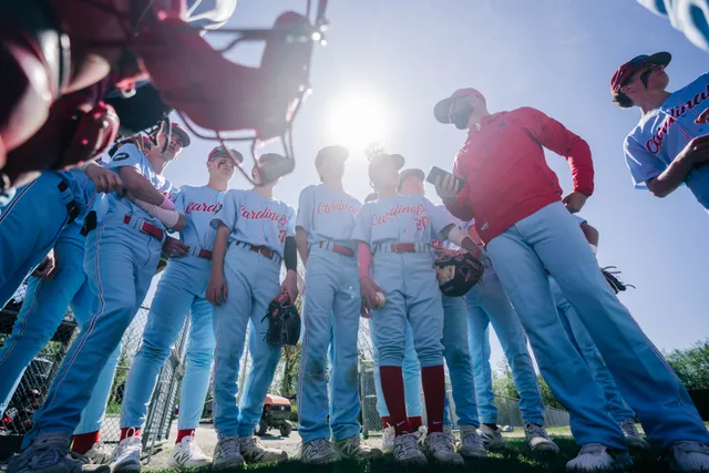 Abbotsford Cardinals players in a low huddle with the sun flaring through them.
