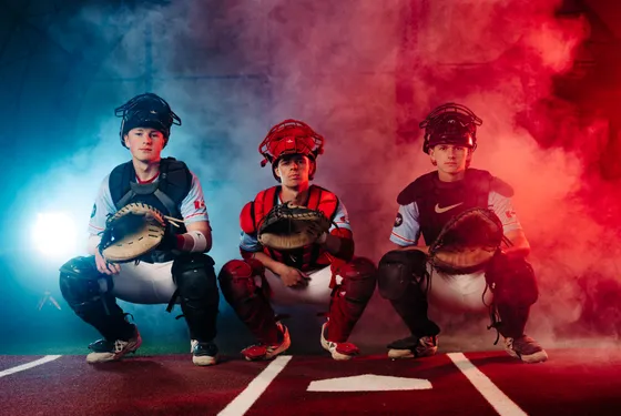 Three Abbotsford Cardinals catchers set in a red and blue lit studio portrait.