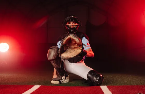 An Abbotsford Cardinals catcher holds his glove out under red studio light.