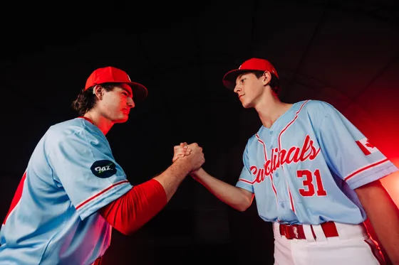 Two Abbotsford Cardinals players grip hands in a studio portrait.